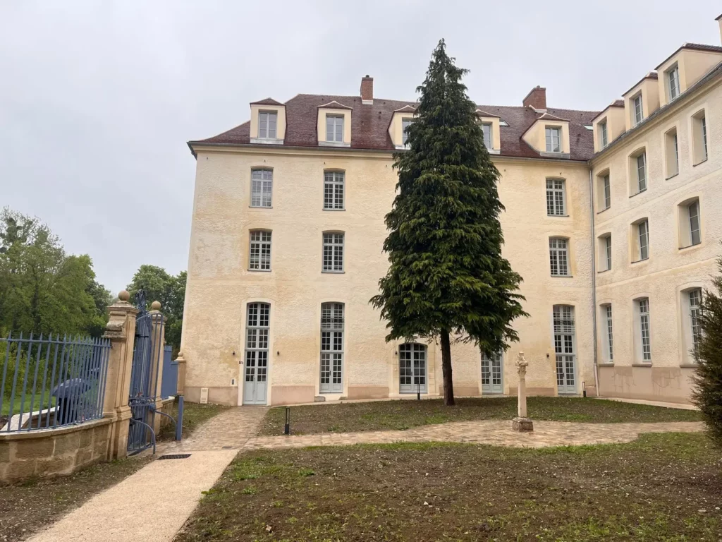 Façade rénovée du bâtiment classé Monument Historique à Juilly avec un sapin conservé