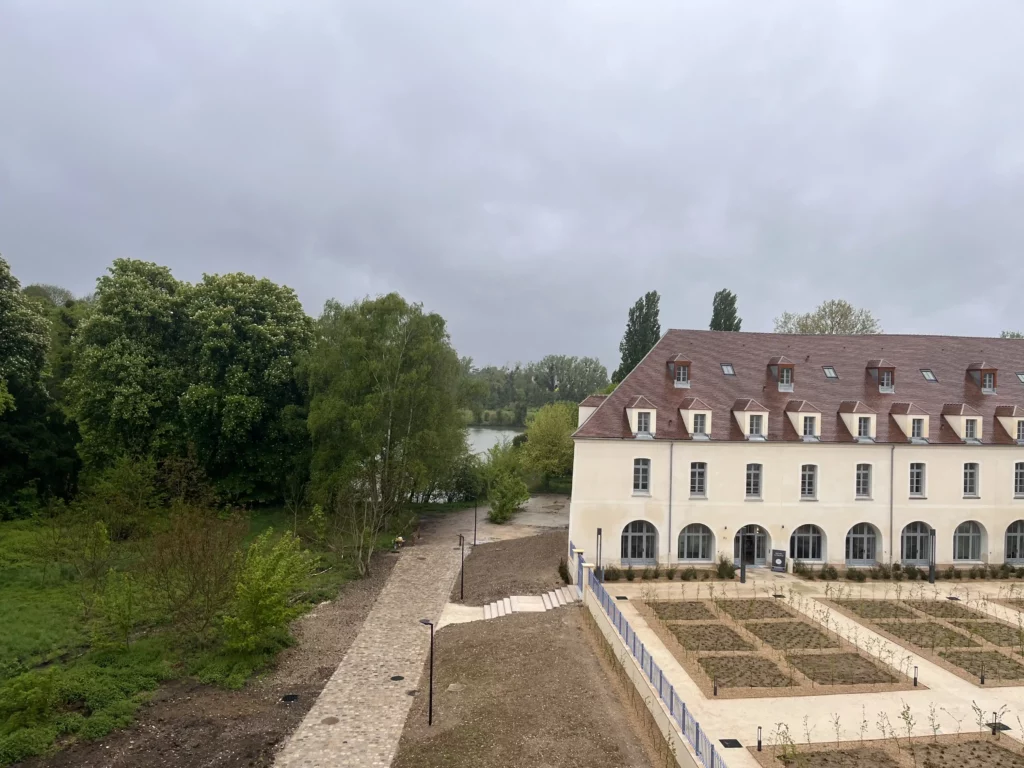 Vue depuis l’appartement sur un bâtiment restauré, la forêt et le lac du domaine de Juilly